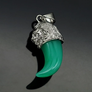 Macro detail of silver lion head pendant with translucent green resin wolf tooth