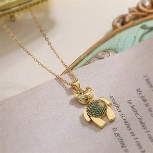 Vue macro d'un collier ours doré serti d'un zircon vert sur un fond de papier vintage