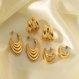 Three pairs of vintage 18K gold-plated stainless steel earrings on beige satin fabric