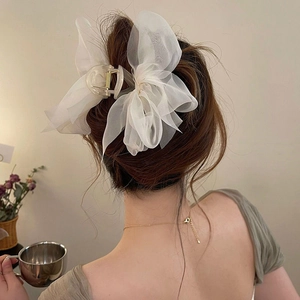 Model wearing white organza double bow hair claw clip in a minimalist indoor setting