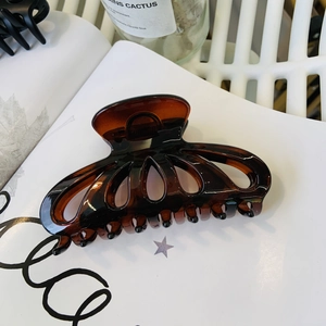 Detailed close-up of large amber petal hair claw clip on a stylish magazine background