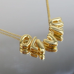 Macro shot of 18k gold plated bubble letter necklace forming the word OLIVE on reflection