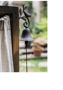 Detail of vintage cast iron doorbell with rustic texture and black pull rope on wood