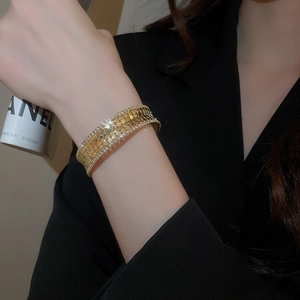 Detail of gold multilayer cuff bracelet with mesh texture and zircon stones on the edge