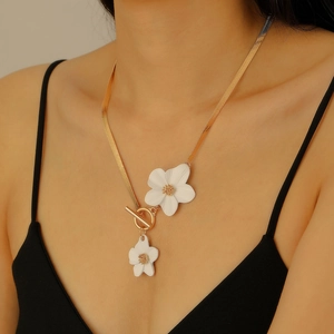 Gros plan d'un élégant collier serpent doré avec pendentifs fleurs blanches sur un mannequin