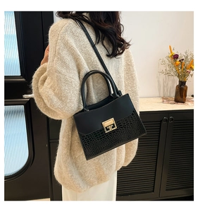 Elegant black faux crocodile skin handbag shown on model wearing white knit sweater