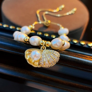 Macro shot of freshwater pearl bracelet with a gold shell pendant and cubic zirconia