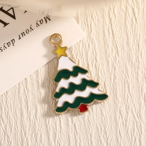 Green enamel Christmas tree pendant with golden star on beige textured background