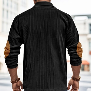 Detail view of corduroy texture and brown elbow patch design on a black men's long sleeve polo