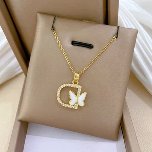 Close-up of golden necklace with D-letter pendant, butterfly inlay and clear crystals