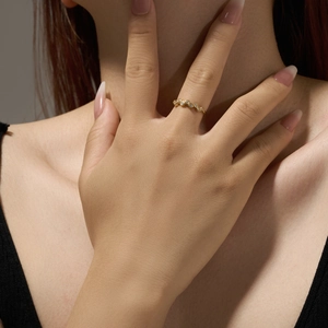Close-up of wavy gold band ring with white zircon stones on a model's finger