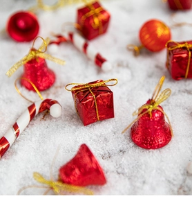 Festive Christmas ornaments with red bells and gift boxes on a snowy white background