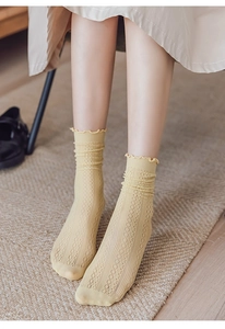 Close-up of yellow sheer hollow-out mesh socks with ruffle edges for women