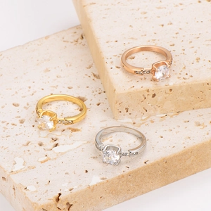 Three-tone stainless steel rings with round cubic zirconia on beige travertine stone