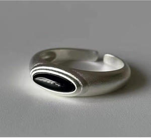 Macro shot of matte silver finish ring with black oval stone and open adjustable design