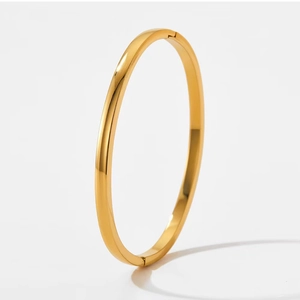 Close-up of polished gold-plated stainless steel bangle showing hinge closure and smooth finish