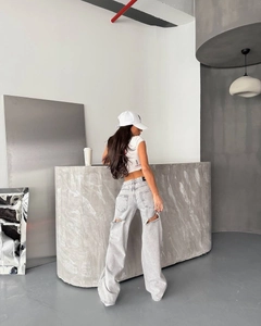 Gros plan d'un jean large gris clair usé avec une découpe stylée à l'arrière de la jambe