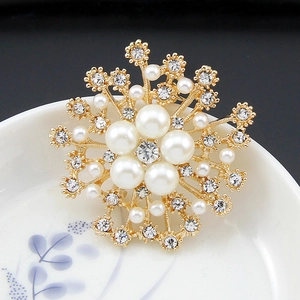 Detailed view of snowflake brooch with pearls and crystals on a ceramic plate
