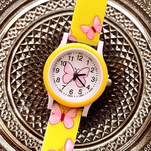 Top view of yellow children's watch with pink butterfly prints and silicone strap on tray