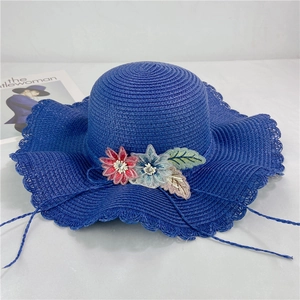 Detail view of blue wide-brim straw hat featuring delicate 3D floral embroidery and wavy edge