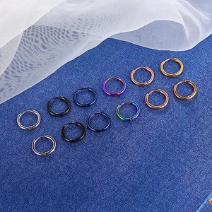 Polished stainless steel hoop earrings in six colors arranged on a blue textured surface