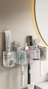 Detail of wall-mounted suction toothbrush holder with wavy glass cups and toothpaste dispenser