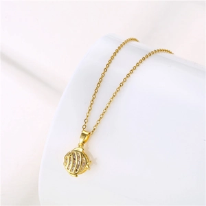 Detail of golden fish pendant necklace with clear zircon stones on a white background