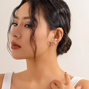 Detailed close-up of a silver bow earring on a model's ear for a minimal fashion look