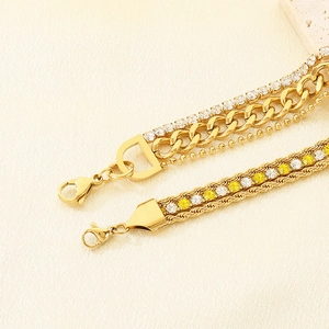 Macro detail of triple-layered gold bracelet with zircon stones and D-pendant charm