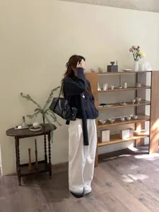 Texture détaillée du pull en maille gris foncé et du pantalon en velours avec pendentif