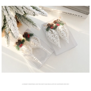 Detailed white glitter Christmas tree ornaments with pine cones on festive greenery
