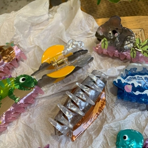 Variety of cute acrylic animal and nature hair clips on a textured background