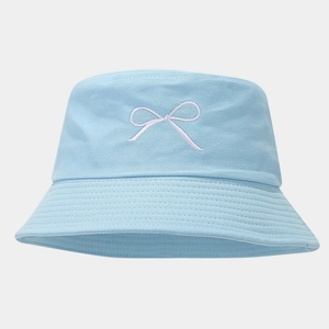 Close-up of light blue bucket hat featuring delicate white bow embroidery and fabric texture