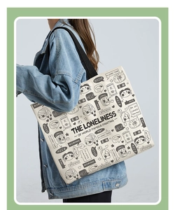 Detail of canvas tote bag with artistic illustration and text shown on shoulder
