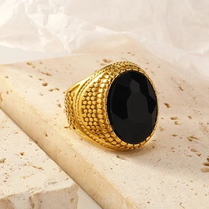 Macro shot of gold-plated signet ring featuring a large oval black gemstone and dotted texture