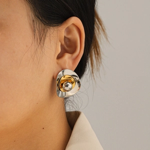 Close-up detail of irregular gold and silver mixed-metal stud earring on model ear