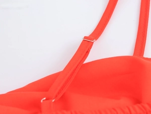 Detailed close-up of adjustable thin spaghetti straps with silver metal slides on orange dress
