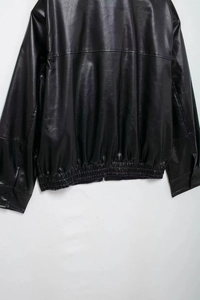 Detail view of the ribbed hem and button cuffs on this black faux leather bomber jacket