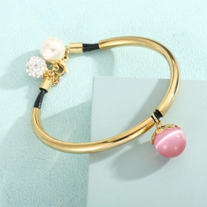 Detail of beaded braided bracelet with pink cat eye stone and golden metal accents