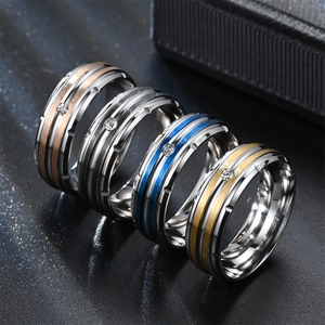 Detail of four brushed titanium steel rings with inlaid zircon on a black background