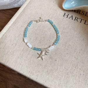 Détail d'un bracelet de perles océan avec breloques étoile de mer et coquillage