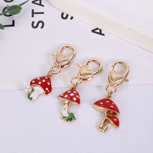 Detailed view of red mushroom charms with gold lobster clasps and white pearl accents