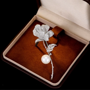 Detail of rose brooch with cubic zirconia petals and a large white pearl in a velvet box