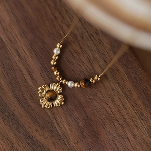 Macro shot of tiger eye stone flower pendant with pearl chain on wooden surface
