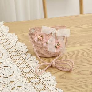 Gros plan d'un sac en paille rose pour enfants avec fleurs en tissu et nœud en dentelle