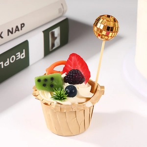 Detail of golden mirror ball cake topper on cupcake with fresh fruit decorations