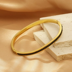 Détail du bracelet en acier titane doré avec insert noir sur fond de soie premium