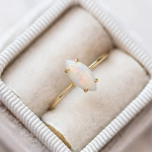 Macro detail of marquise cut opal stone with four-prong setting on a gold ring band