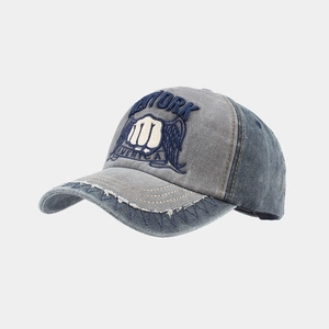 Close-up of vintage washed denim baseball cap featuring fist embroidery and distressed details