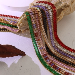 Colorful zircon tennis bracelets in gold plating set against white stone and rustic wood